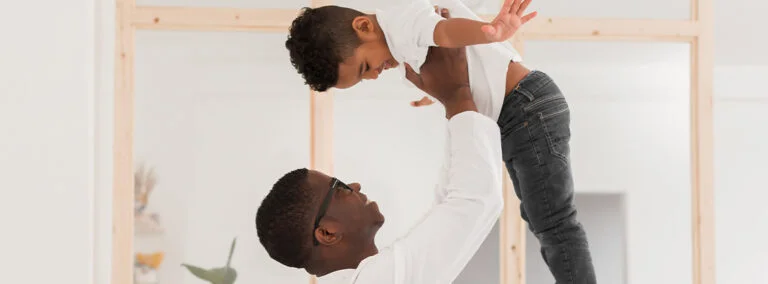 A father playing with is son at home during lockdown, lifting his son into the air above his head. PR and affiliate marketing case study results for Menkind.